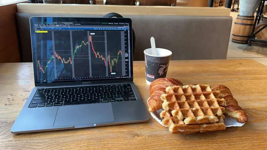 A laptop, coffee, and waffles at a café table.