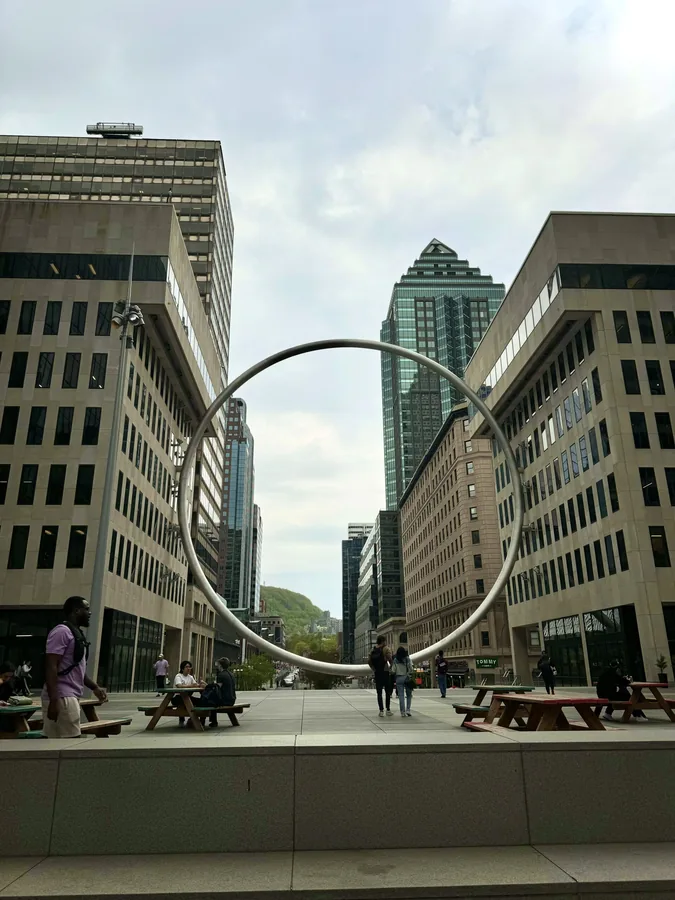 A circular sculpture framed by downtown buildings.