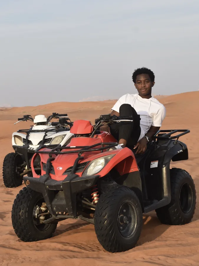 A traveler beside a red quad bike in the desert.