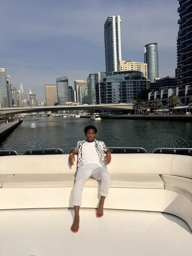 A traveler seated on a boat in front of Dubai’s skyline.