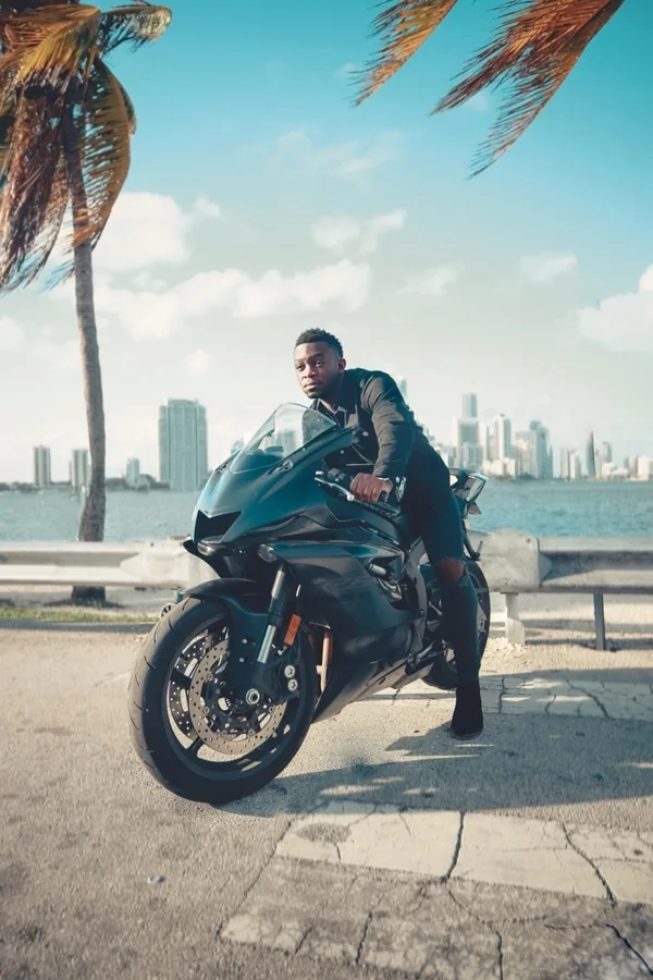 A motorcyclist beside the water and palm trees in Miami.