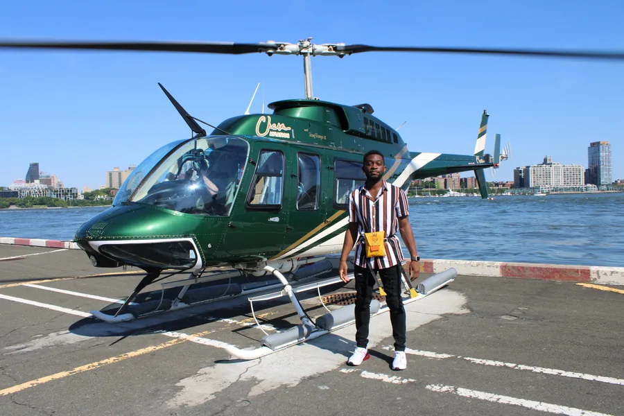A traveler beside a helicopter with the New York waterfront behind them.