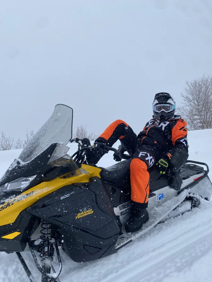 A rider on a snowmobile in a snowy landscape.